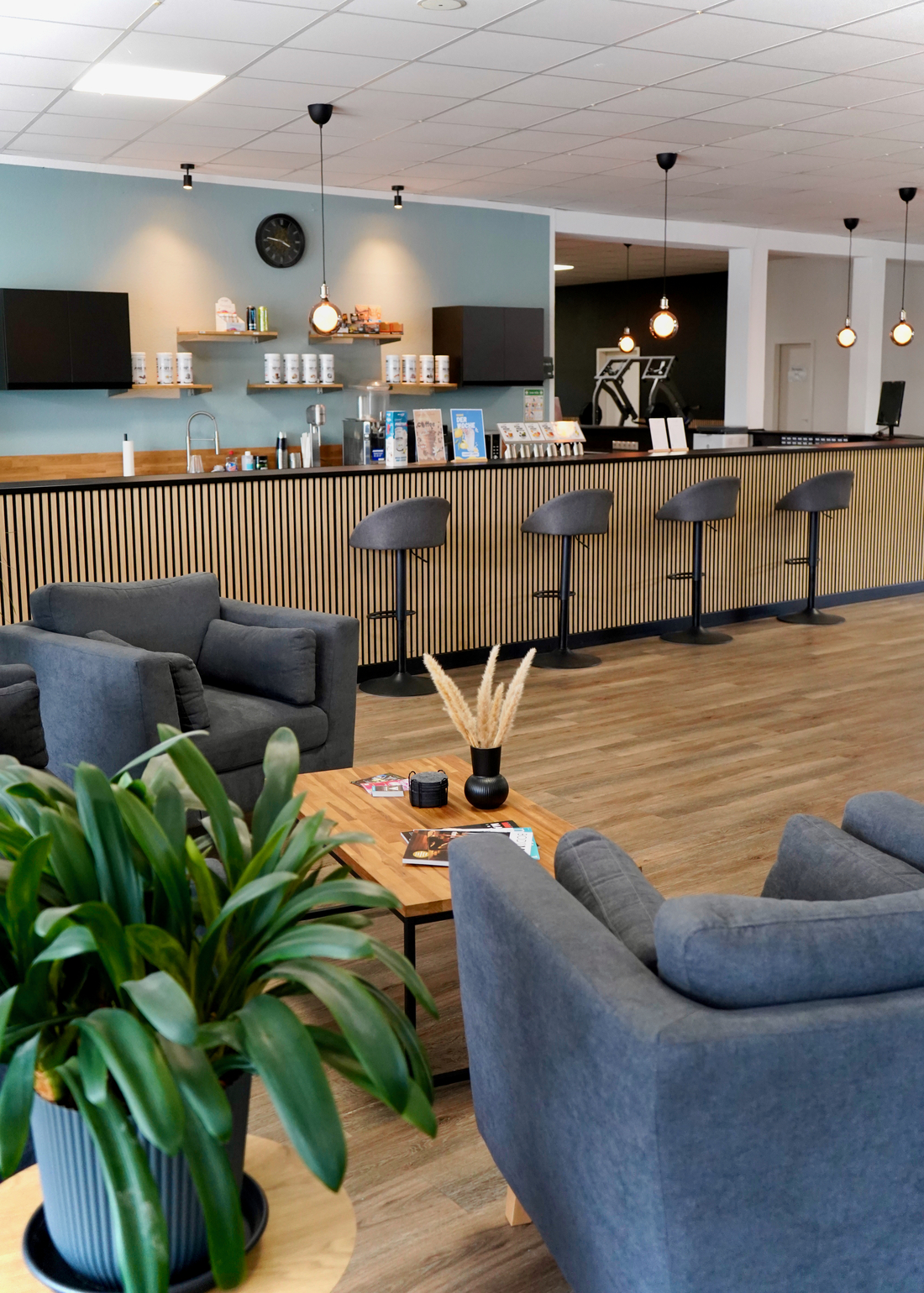 Eine moderne Lounge mit grauen Sesseln und Holztheke in warmen Farben