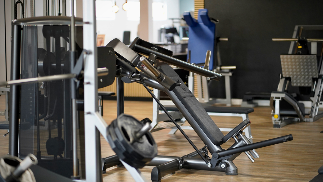 Ein modernes Fitnessstudio mit schwarzen Trainingsgeräten auf hellem Holzboden