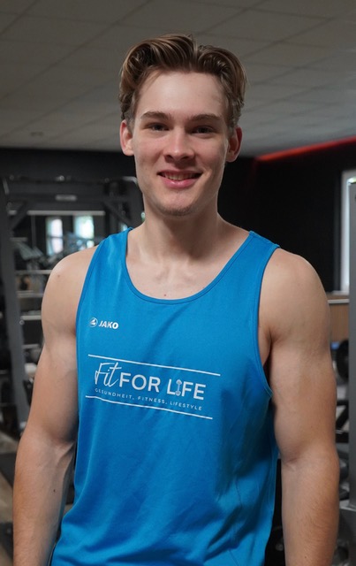 Laechelnder junger Mann im blauen Fit for Life Traegershirt im Fitnessstudio