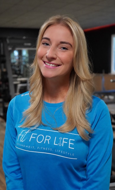 Laechelnde blonde Frau im blauen Fit for Life Shirt in einem Fitnessstudio
